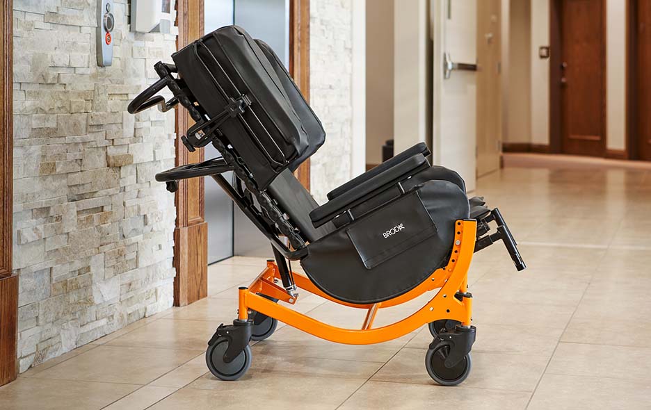 A Broda Wheelchair tilted in a facility hallway