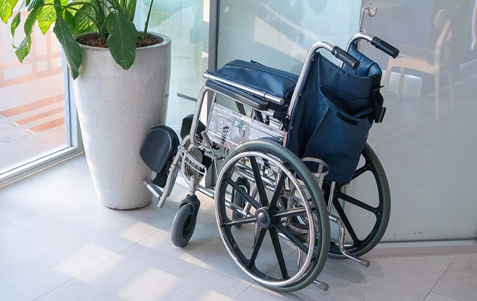Collapsed sling seat wheel chair placed near a wall
