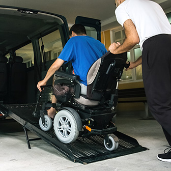 NEMT operator escorting a wheelchair passenger up a ramp
