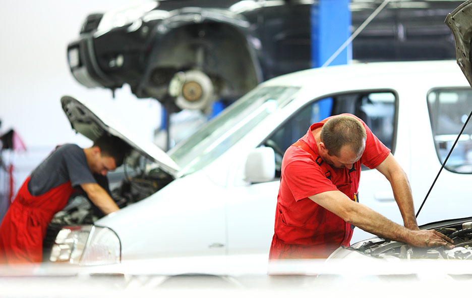 Car mechanics working on vans side-by-side