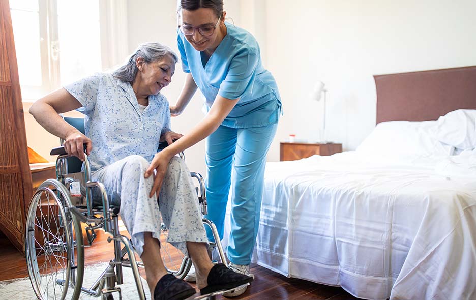 Healthcare worker helping a patient in to her wheelchair