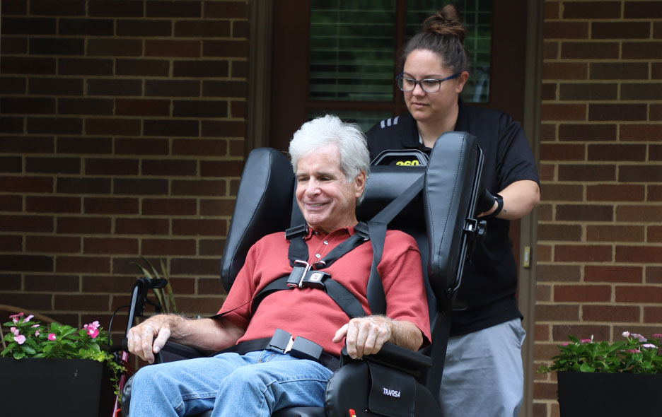 Man in NEMT Wheelchair Being Pushed From Behind By a Healthcare Worker